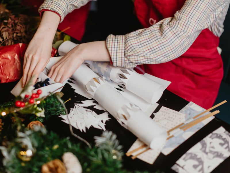 Person in red apron making Christmas crackers